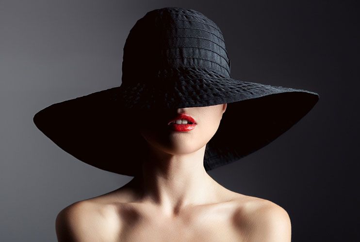 A woman with red lipstick and a black hat.